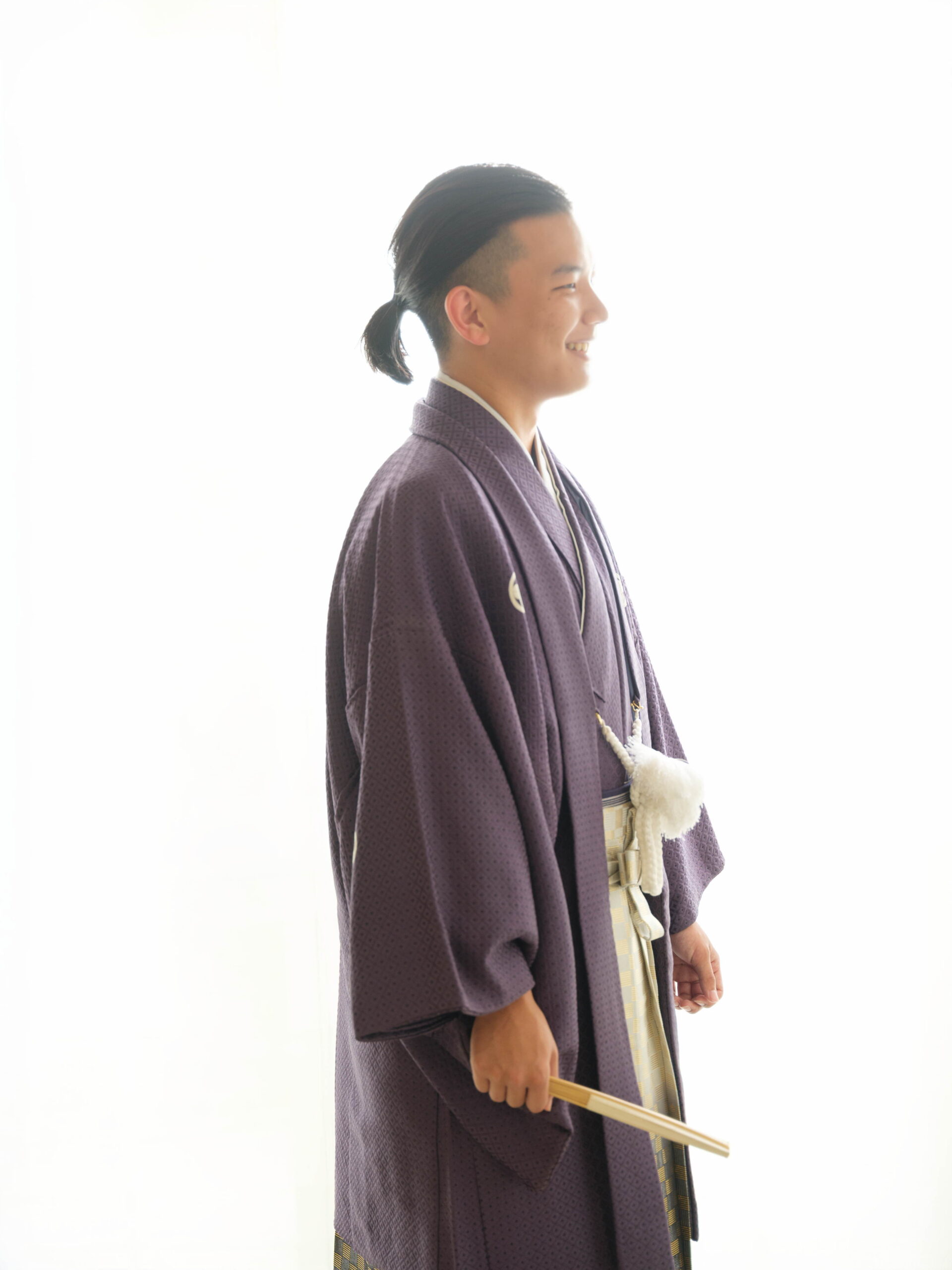 紫の羽織袴を着た男性の横向きのスタジオ撮影